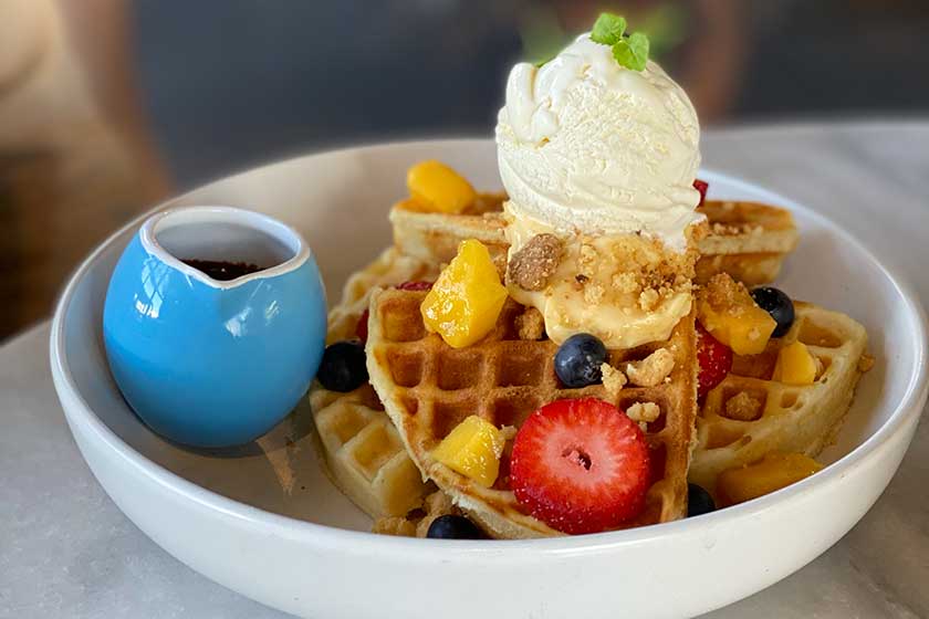 Buttermilk waffles served with lemon curd, almond crumble, seasonal fruits, chocolate sauce and vanilla ice cream